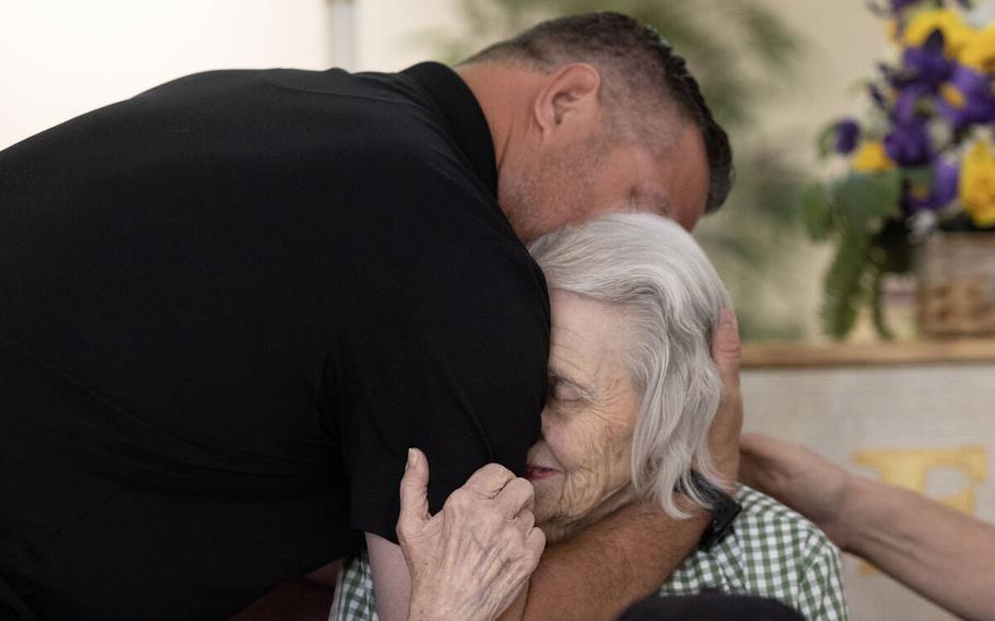 A man embraces a seated centinarian, his grandmother.