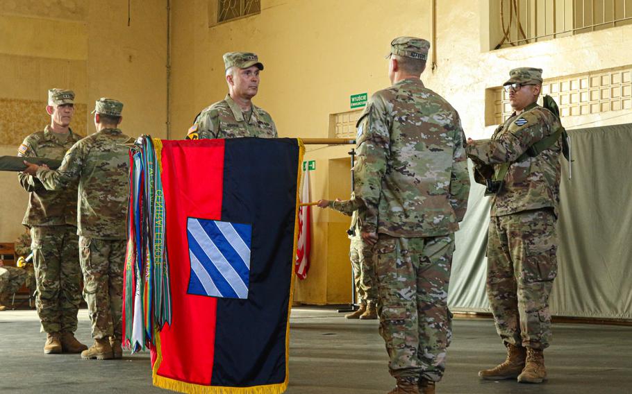 Army Command Sgt. Maj. Jonathan Reffeor and Maj. Gen. Christopher Norrie from the 3rd Infantry Division uncase and unfurl the battalion colors during a transfer of authority ceremony in Boleslawiec, Poland, on Sept. 9, 2023. 