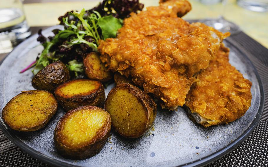 A gluten-free twist elevates the Milanese-style veal chop dish featuring a cornflake and parmesan crust at Grifo Restaurant in Kerzenheim, Germany. Paired with roasted potatoes and lime mayo, it offers a fusion of traditional flavors with a modern twist.