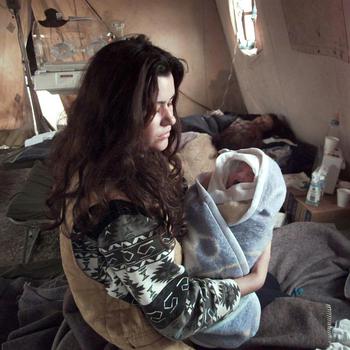 A Kosovo refugee tries to comfort her crying newborn baby inside the maternity tent of the Israeli Defense Force hospital. There have been 9 births inside this refugee medical facility, located at the Brazda Refugee camp in Skopje Macedonia. 