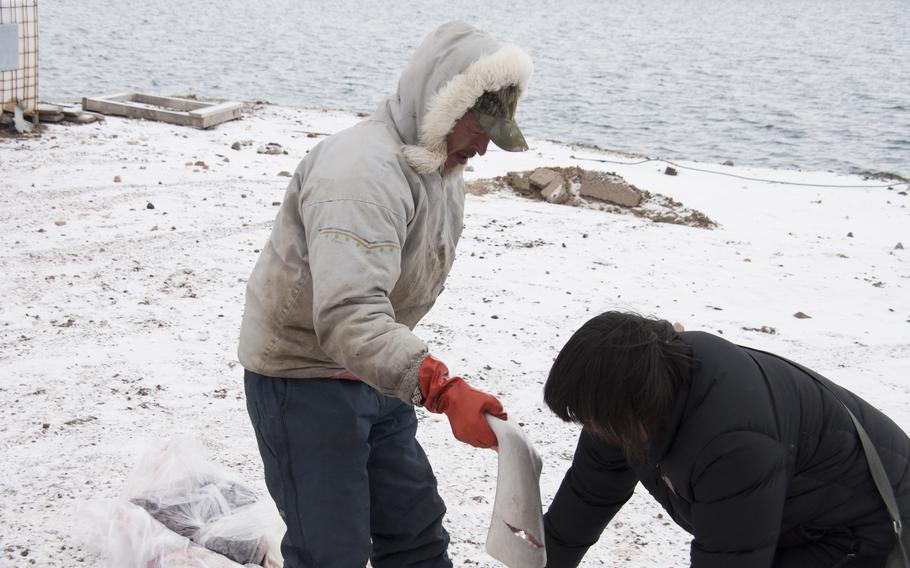 One of the many Greenlandic contractors working on Thule buys a piece of beluga whale from an Inuit man from the nearest village, Qaanaaq.
