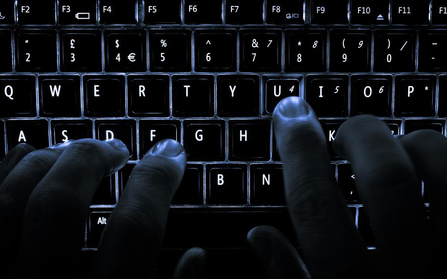 A backlit keyboard with hands hovering above it.