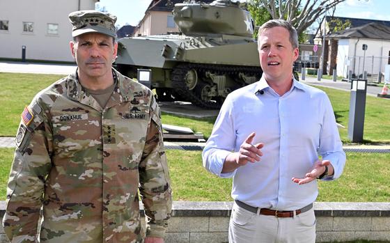 Army Secretary Daniel Driscoll speaks to reporters April 9, 2025, at Clay Kaserne in Wiesbaden, Germany, as U.S. Army Europe and Africa commander Gen. Christopher Donahue listens. In the background is a World War II-era M4 Sherman tank.
