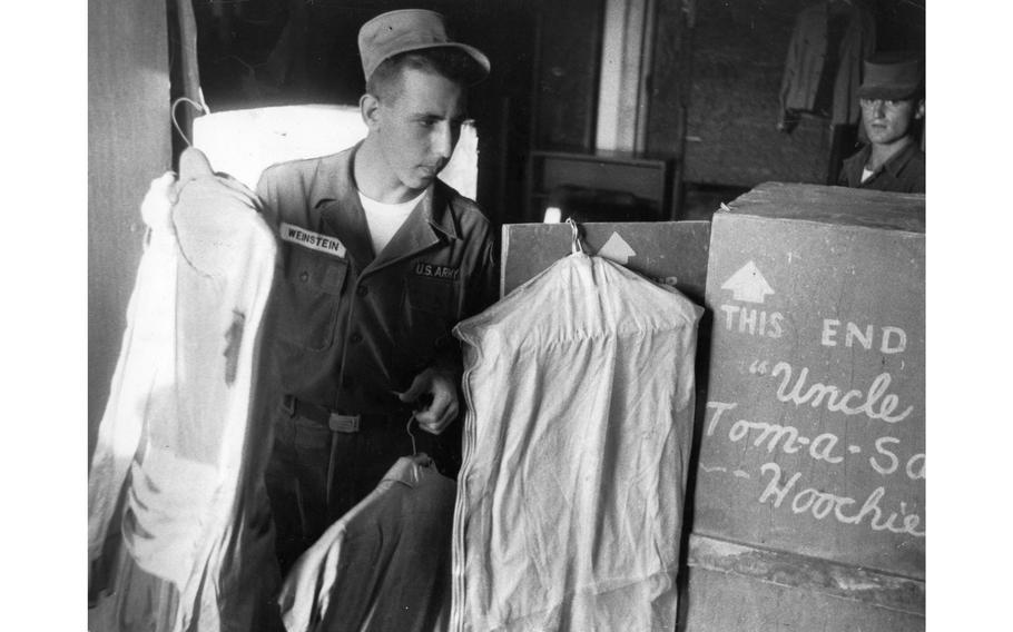 A 7th infantry Division soldier identified by his name tag as Weinstein sorts through various bagged costumes for performance later that day.