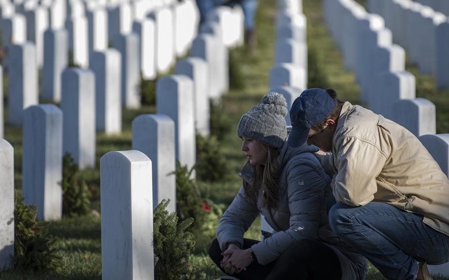 Zach Deatherage comforts Ansley Schoen as they spend time before the headstone of  Michael Hart, a close family friend of Schoen’s.at Arlington National Cemetery on Saturday, Dec. 17, 2022, during the annual Wreaths Across America event that saw more than a quarter-million wreaths laid on Arlington tombstones.