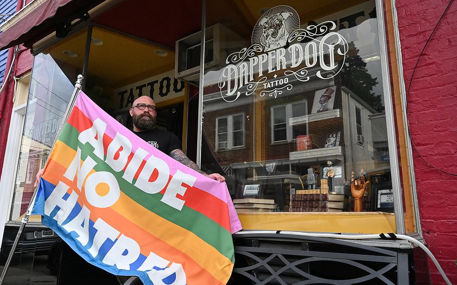 A person holds a rainbow flag that says “ABIDE NO HATRED”