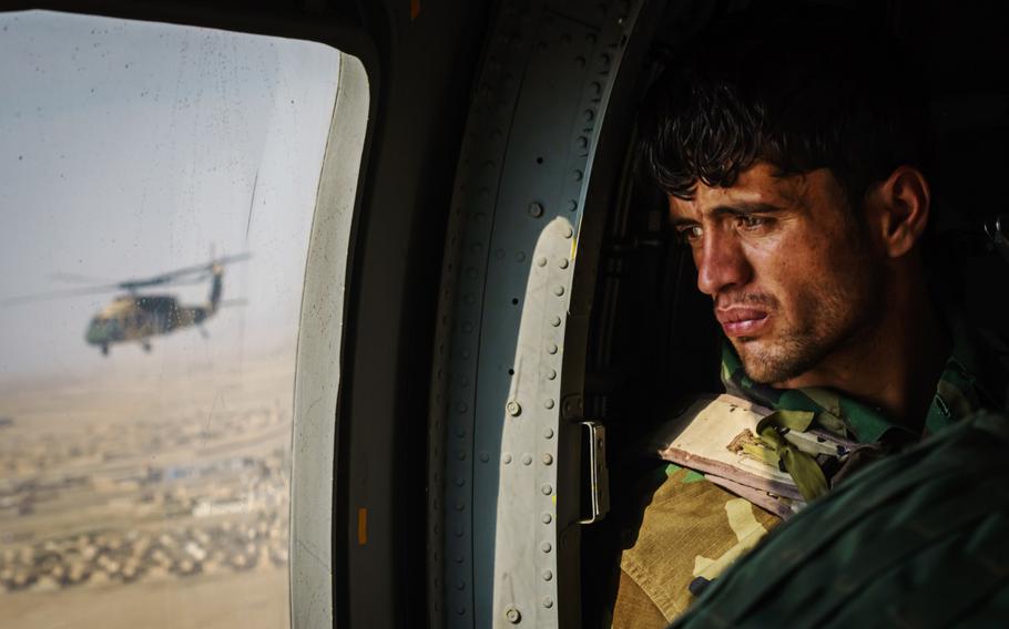 A soldier surveys the terrain out the window during a resupply flight on a UH-60 Blackhawk toward an outpost in the Shah Wali Kot district north of Kandahar, Afghanistan, on May 6, 2021.