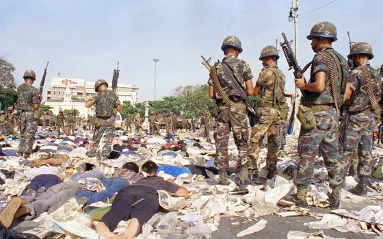FILE - Government soldiers stand over pro-democracy protesters demanding the resignation of Suchinda Kraprayoon, who surrendered after they moved in firing automatic weapons in the air in an attempt to clear the area near Phan Fa Bridge in Bangkok, May 18, 1992. (AP Photo/Nate Thayer, file)