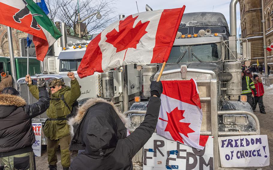 A woman waves a flag and cheers on truckers in protest of COVID-19 vaccine mandates on Jan. 30, 2022, in Ottawa, Canada. Thousands turned up over the weekend to rally in support of truckers using their vehicles to block access to Parliament Hill, most of the downtown area Ottawa, and the Alberta border in hopes of pressuring the government to roll back COVID-19 public health regulations.