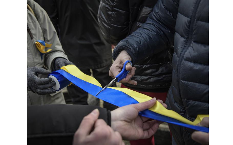 Russian, Belarussian and some Ukrainian youth gather at Tbilisi sea to participate at burning the doll of Russian president Vladimir Putin doll as a part of pagan rituals marking end of winter season and beginning of spring in Tbilisi, Georgia, on March 27, 2022. Here they are cutting yellow and blue ribbon for participants to represent Ukraine.