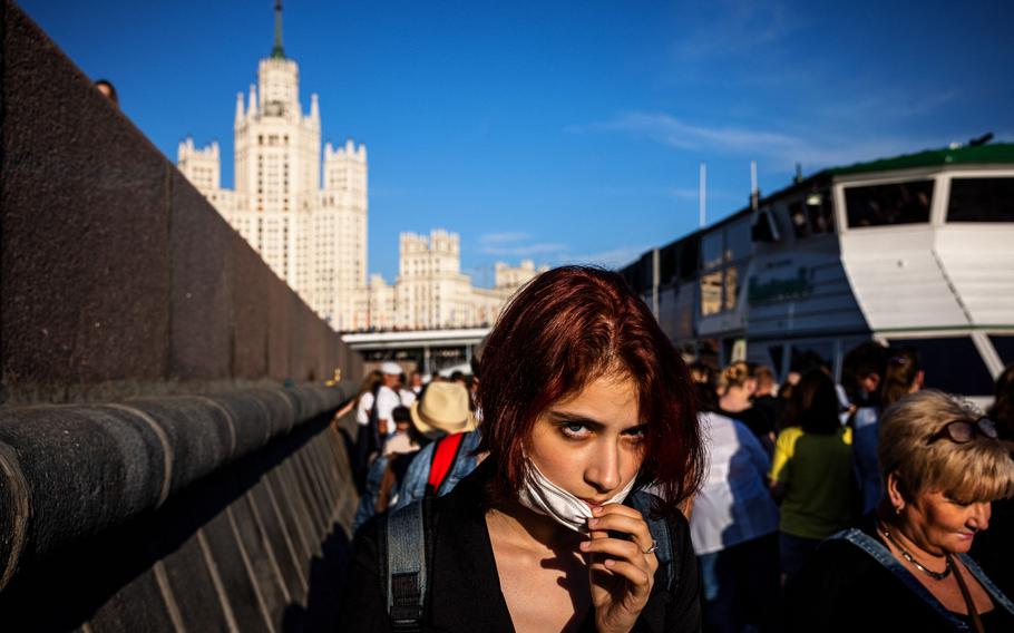 A woman adjusts her protective face mask while waiting to board a cruise boat trip along the Moskva river in Moscow on June 13, 2021. 