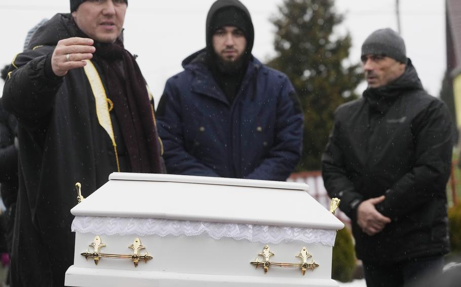 A Polish imam, left, and two other members of a Muslim community bury the tiny white casket of an unborn Iraqi boy, in Bohoniki, Poland, on Tuesday Nov. 23, 2021. The child is the latest life claimed as thousands of migrants from the Middle East have sought to enter the European Union but found their path cut off by a military build-up and fast approaching winter in the forests of Poland and Belarus. (AP Photo/Czarek Sokolowski)