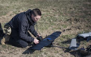 A soldier tests a homemade drone in a field.