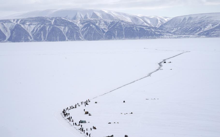 Families fish along a crack in the sea ice. The community relies on fishing and hunting for subsistence. 