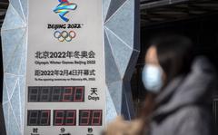 A woman wearing a face mask to protect against COVID-19 walks past a clock counting down the time until the opening ceremony of the 2022 Winter Olympics in Beijing, Saturday, Jan. 15, 2022. Beijing has reported its first local omicron infection, according to state media, weeks before the Olympic Winter Games is due to start.