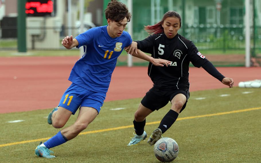 Yokota's Senna Solberg and Zama's Jayrielle Sungalo chase the ball during Monday's Division II boys soccer match. The Trojans won 1-0.