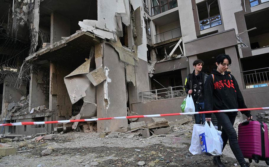 Residents carry their belongings as they leave their damaged building following Russian strikes in Kyiv on April 29, 2022, amid Russian invasion of Ukraine. 