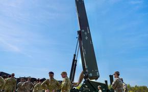 Soliders stand in front of the Dark Eagle hypersonic missile system with a blue sky in the background.