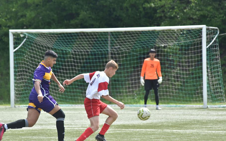 Aviano's Anthony Davis passes in front of the goal while Bahrain's Ghady Mukatash follows behind on Monday, May 15, 2023, in the first round of the DODEA-Europe Division II soccer championships in Baumholder, Germany.
