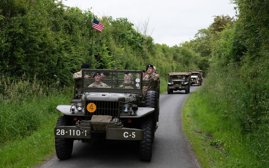 Soldiers ride in a vintage military vehicle.