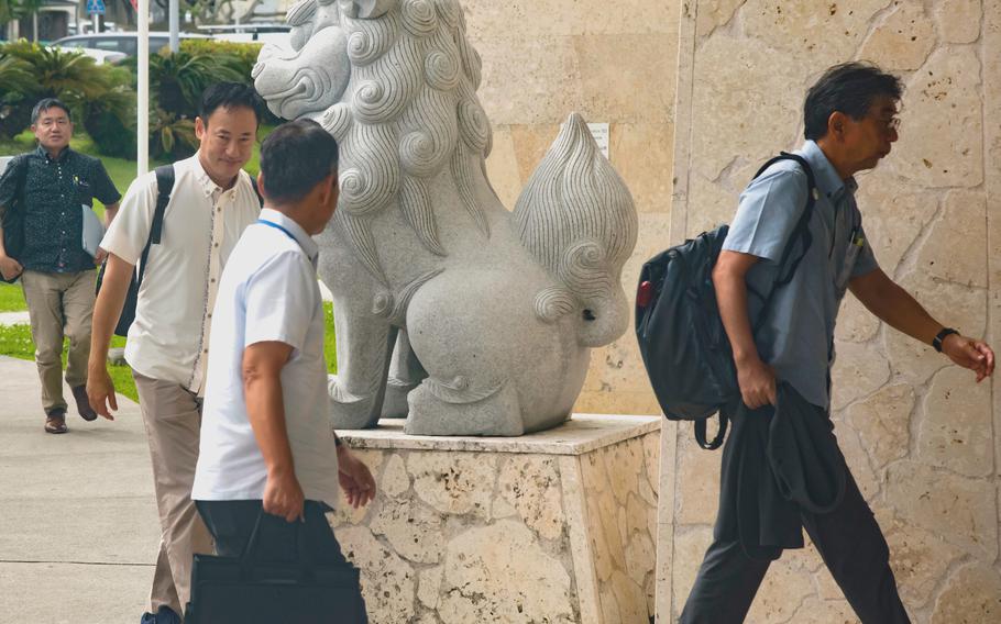 Four Japanese officials walk by a statue at Camp Foster as they head to a community partnership forum.