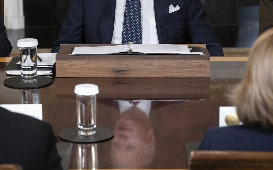 Reflected on a table, President Biden hosts a meeting with Defense Department leaders at the White House on Oct. 26, 2022.