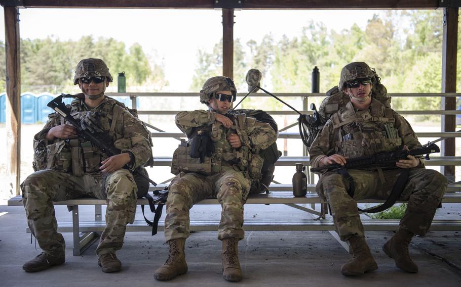 Three soldiers smiling and sitting on a bench.