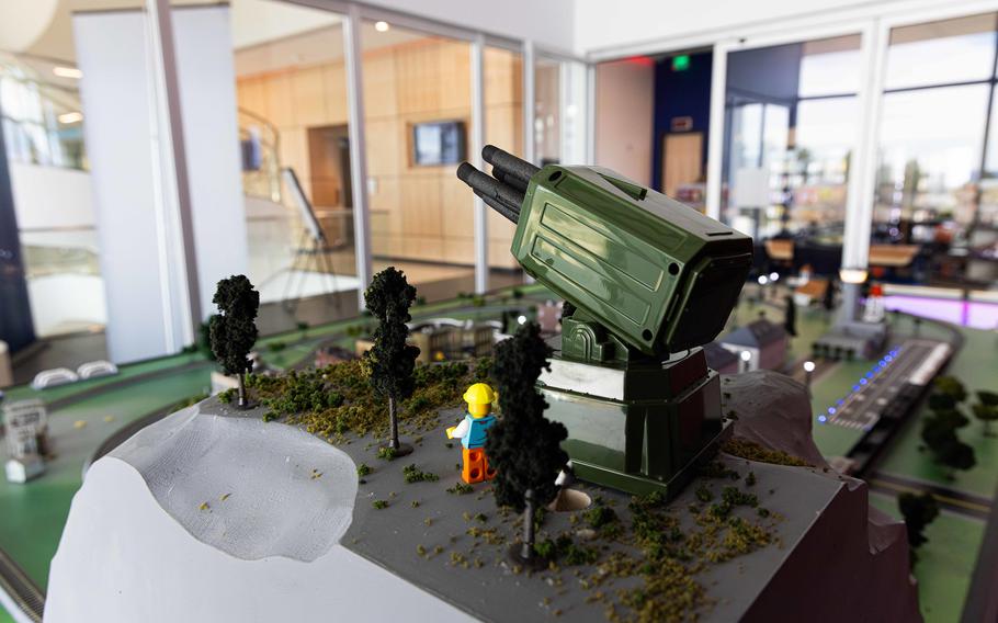 A closeup of a Lego-like figure next to a model artillery launcher.