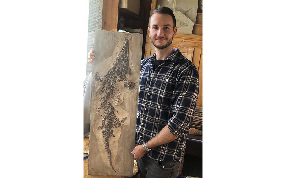 Palaeontologist Dean Lomax holds up a cast of an ichthyosaur.