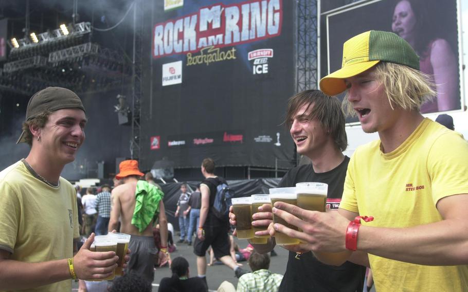 Three young men hold glasses of beer.