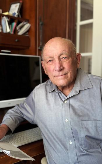 A Vietnam veteran poses for a photo in front of a computer screen. 