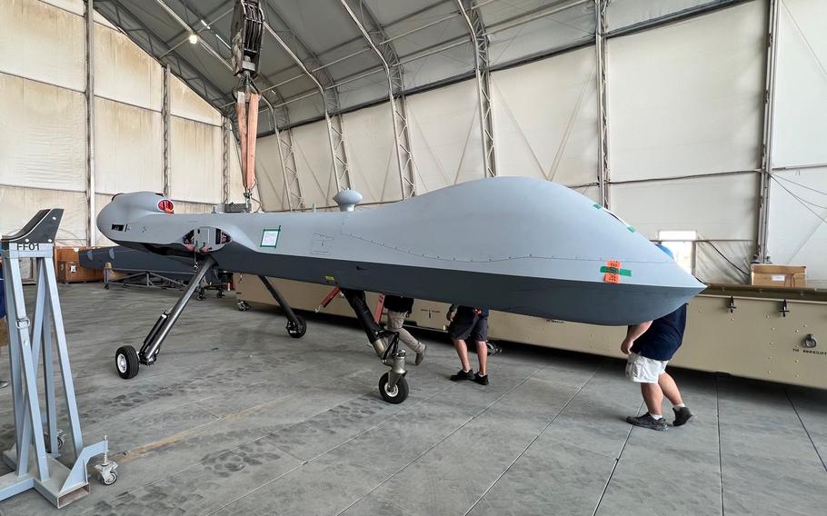 Workers walk past a recently assembled Marine Corps MQ-9A Reaper aerial drone in a hangar in the Middle East on Sept. 8, 2023.