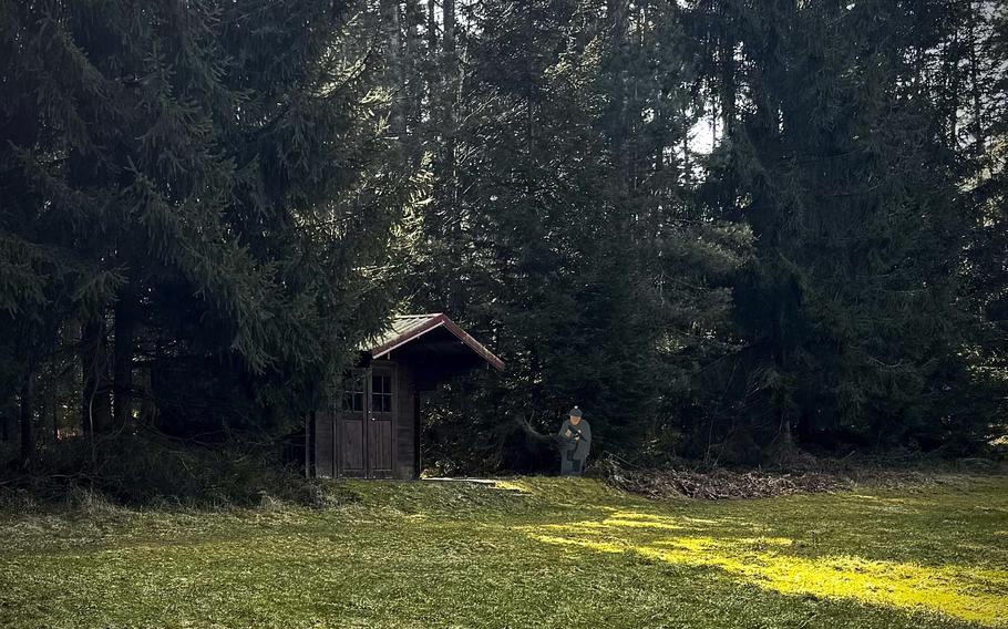 A small hut under trees in the forest with grass in the foreground