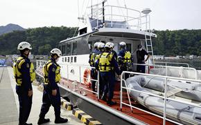 Hokkaido prefectural police officers board a patrol boat for a search operation Thursday. MUST CREDIT: Japan News-Yomiuri.