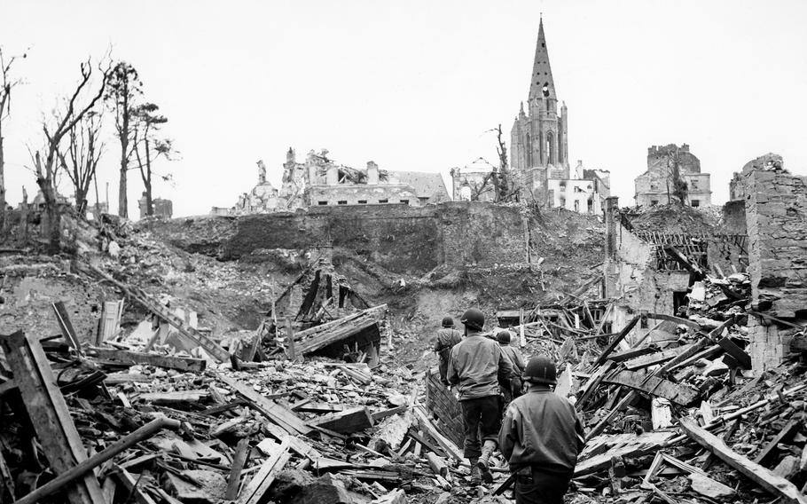 An American infantry patrol picks its way through the ruins of Saint-Lo, France, during mopping up operations against the Germans. The town was 95% destroyed before it was captured from Germans on July 18, 1944. Some 50% of the town’s church of Notre Dame de Saint-Lo, whose south bell tower can be seen in the background, was destroyed. The south tower would lose its spire in the days after this photograph was taken. After the war the decision was made to only partially restore the church as a memorial of the destruction of the city of Saint-Lo.
