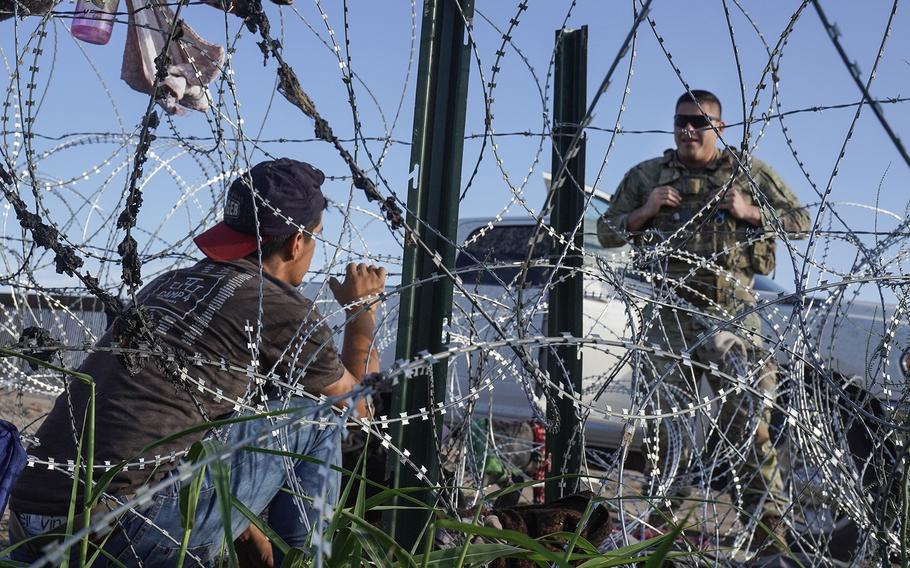 A member of the U.S. National Guard tells a Venezuelan migrant to turn back Thursday, Sept. 21, 2023, as he tries to negotiate razor wire along the border in Ciudad Juárez, Mexico. 