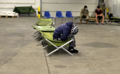 An Afghan woman sits alone in the medical area of a warehouse that has been transformed into a processing center for evacuees on Rhine Ordnance Barracks in Kaiserslautern, Germany, Aug. 30, 2021. Many of the Afghans who are being temporarily housed at the Army facility are suffering from depression and survivor guilt for those they left behind in Afghanistan, medical staff say.