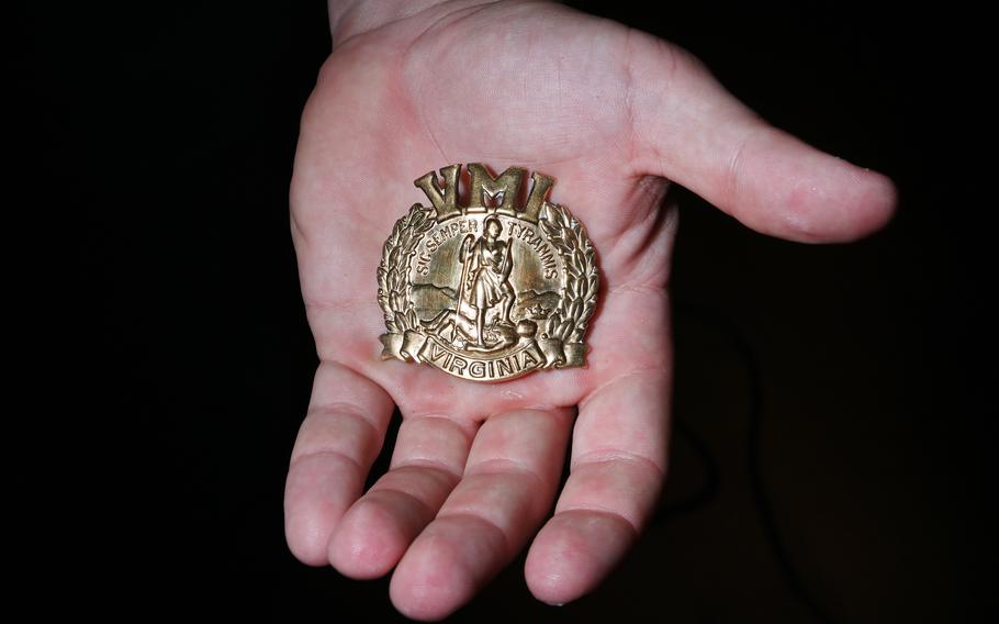 Robert holds a VMI hat insignia. 