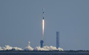 A rocket launching from a launch pad against a blue sky.