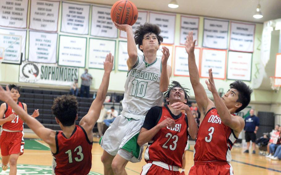 Kubasaki’s Troy Harris vaults to shoot over three Okinawa Christian  defenders during Tuesday’s Okinawa boys basketball game. The Dragons beat the Eagles 66-52.