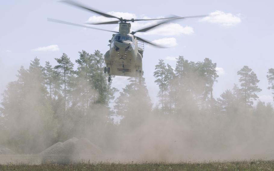 A helicopter near the ground kicks up dust.