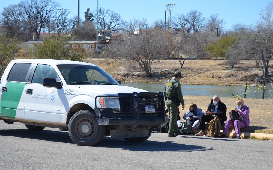 A Border Patrol agent detains a group of people who illegally crossed into the U.S. from Mexico in Eagle Pass, Texas, on Feb. 14, 2022. The Texas National Guard also patrol in this area and alert the federal agents when they see people as part of a state border security mission. 