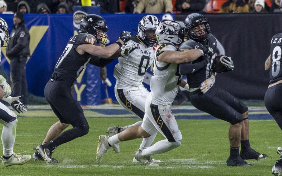 A Navy defensive player wraps up an Army running back.