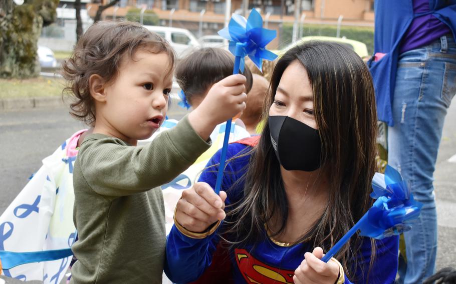 Sari Sugai, Exceptional Family Member Program manager for Army Community Service, helps Ezra Stallings, 2, plant a pinwheel at the Child Development Center at the Sagamihara Family Housing Area, Japan, April 9, 2021. The 2022 Army budget proposal would provide $3.3 million to hire case managers for the Exceptional Family Member Program, which help families with special medical or educational needs, and others to focus on the oversight of Army family housing construction and repair.