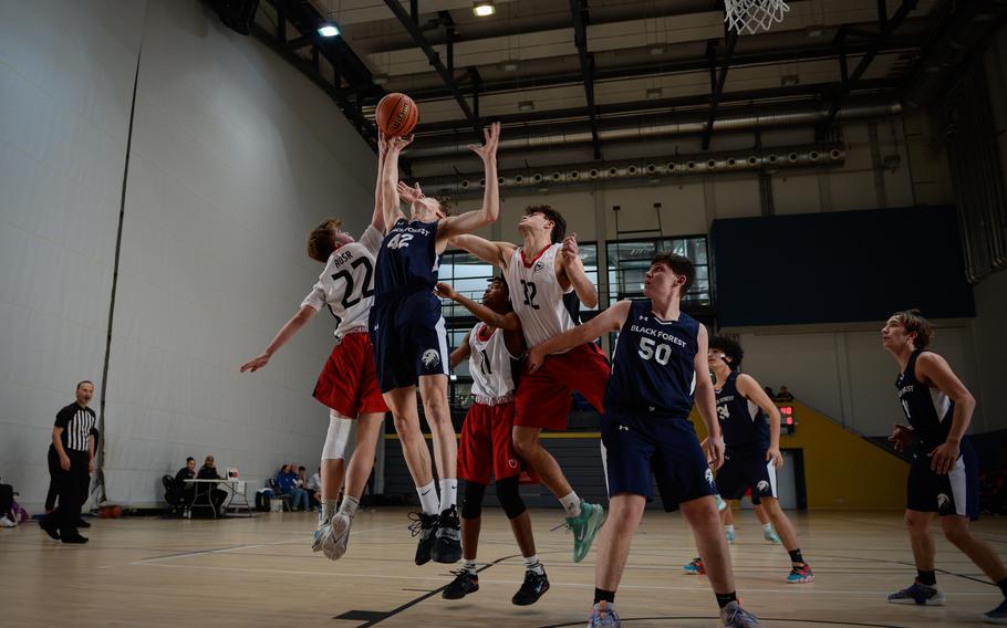 Black Forest Academy Falcon Asher Wendler tries for a rebound against Riley Smith, Nahom Dehenie and Gabriele Ghione of American Overseas School of Rome during the DODEA-Europe Division II boys basketball tournament Wednesday, Feb. 15, 2023, at Ramstein Air Base. 