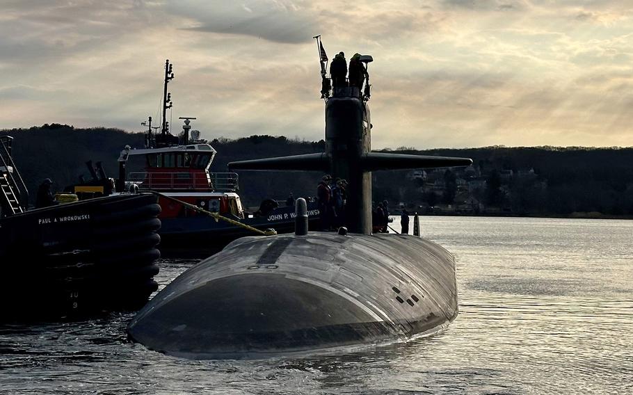 Tugboats guide the attack submarine USS Newport News away from the pier.