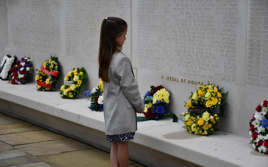 A girl pays her respects at the Wall of the Missing during the Memorial Day ceremony at the Cambridge American Cemetery on Monday, May 30, 2022.