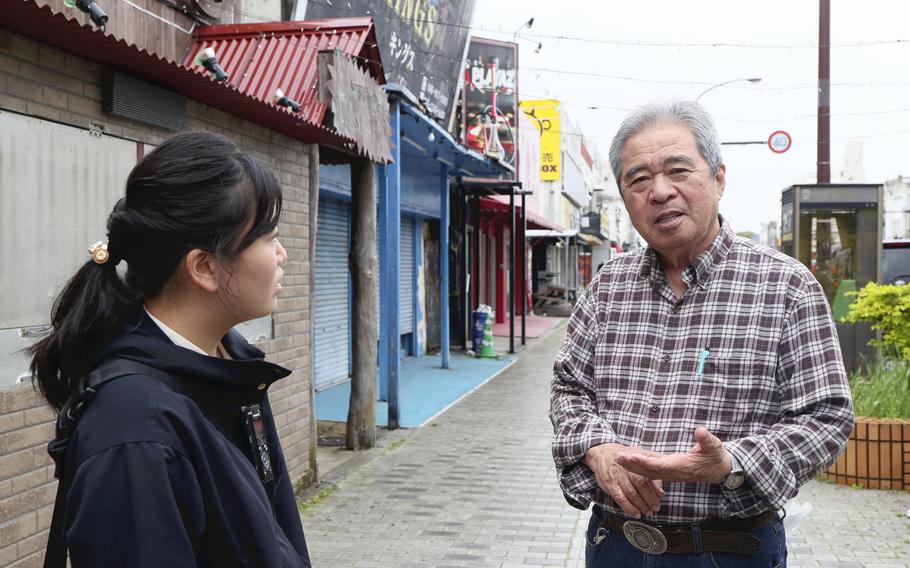 Seiji Tokutomi talks to a student about Koza’s history in Okinawa City, Okinawa Prefecture, in March. 