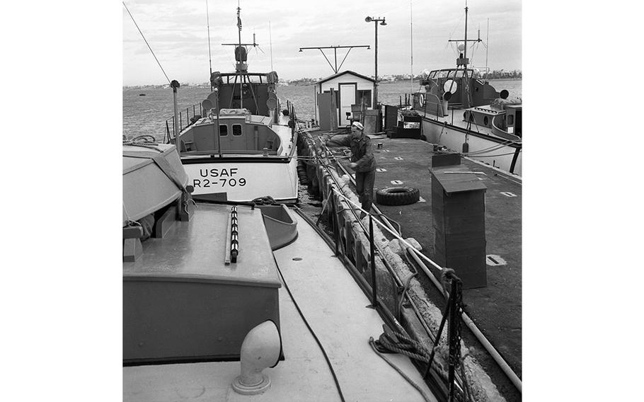 Airman 2nd Class Alvin R. Penry, looking like a sailor, tosses rope onto his PT boat, moored at Tripoli harbor, Libya. The men of the 7th Crash Rescue Boat Flight run four 63-foot converted PT boats that provide marine rescue services in the event of an air crash at sea. More than half of the 38 airmen comprising the 7th Flight have had previous experience swabbing decks. Many served on torpedo boats in World War II and signed up with the Air Force specifically to get crash boat duty. 