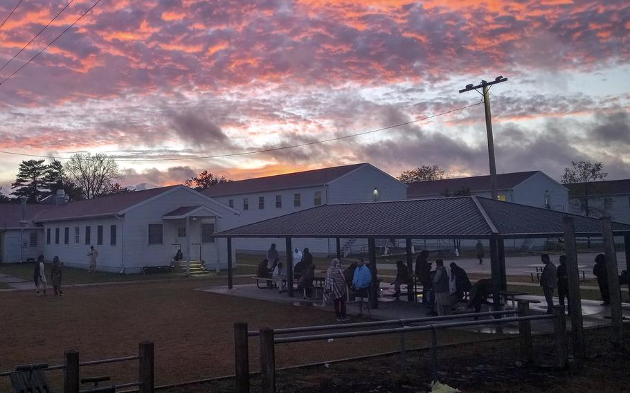 Afghan evacuees gather to talk Sept. 24, 2021, as the sun sets over Fort McCoy, Wis., where they are waiting to be resettled.